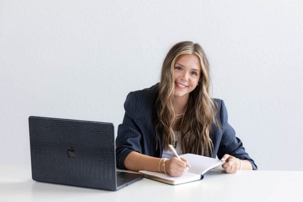 Professional Oklahoma Estate Lawyer Working with Clients Smiling young professional writing in notebook, representing an Oklahoma Estate Lawyer in a modern workspace.
