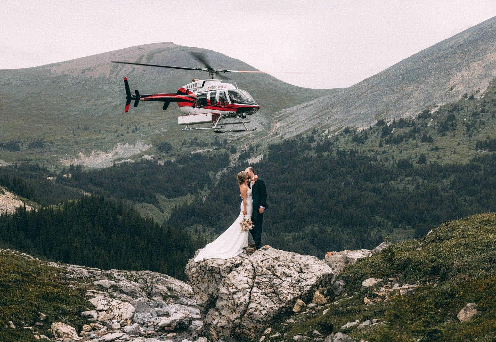 couple standing under a helicopter on the mountaons