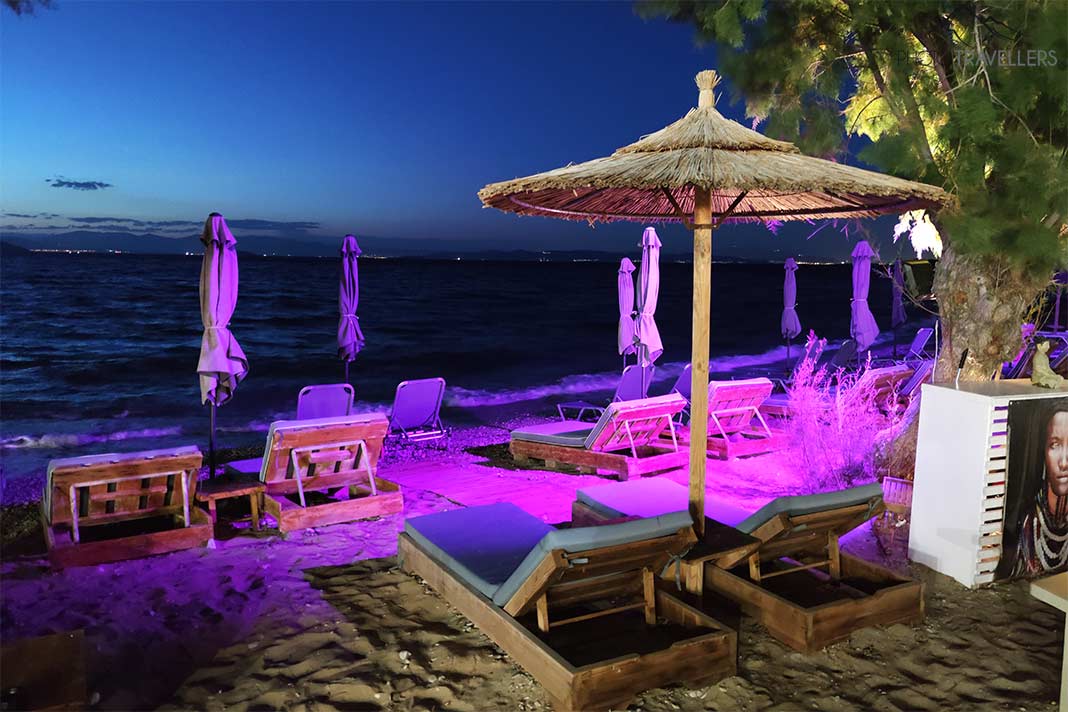 Die Liegen und Sonnenschirme am Skala Beach werden nachts in pink angestrahlt