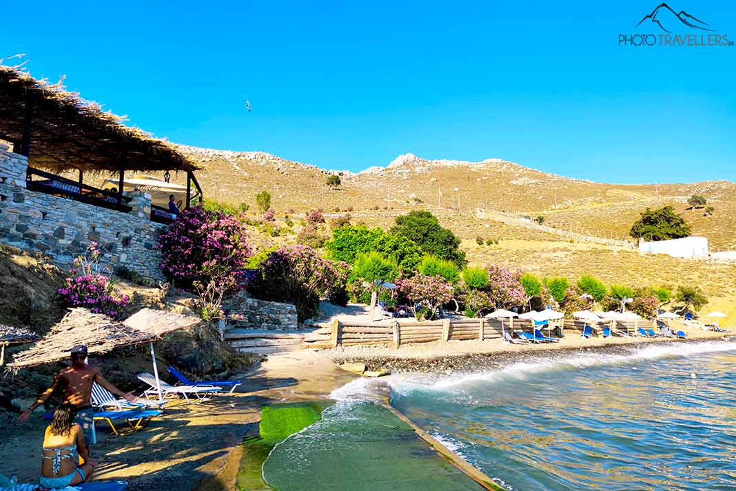 Einige Menschen sonnen sich am schmalen Kiesstrand von Toli Beach