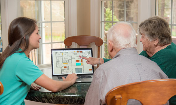 Smooth Transitions team member reviews a floor plan on a laptop with a senior couple during a move planning consult