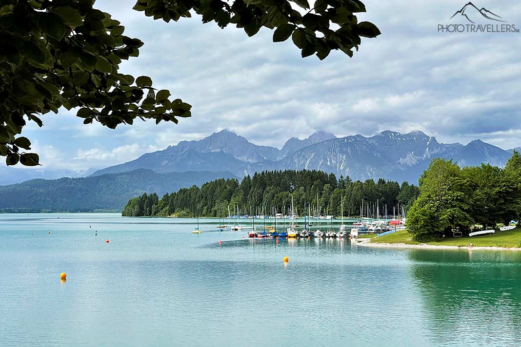 Der Blick über den Forggensee mit Booten und Bergen dahinter