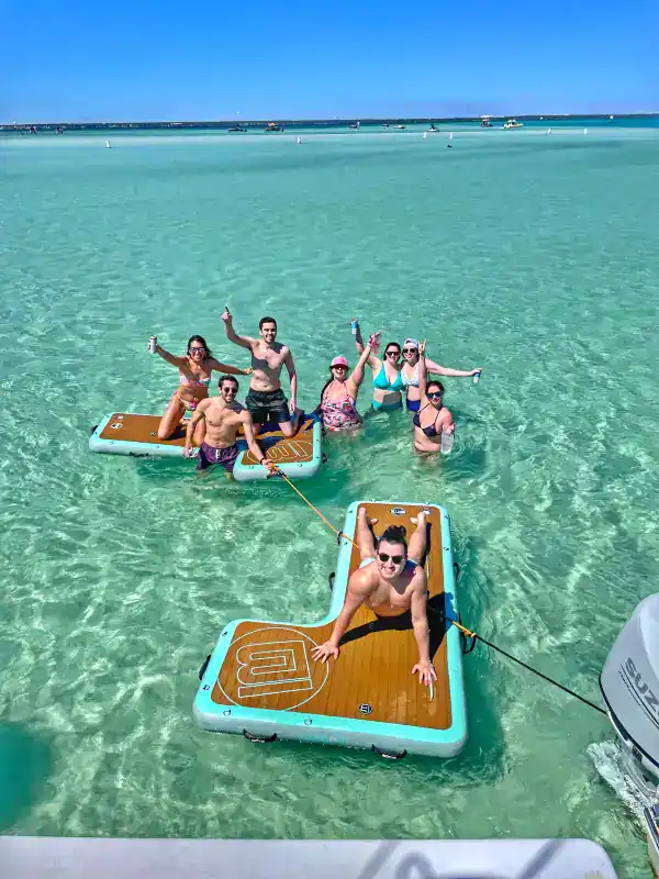 Group of people on BOTE floats with Crab Island Luxury Adventures, playing at Crab Island next to their catamaran