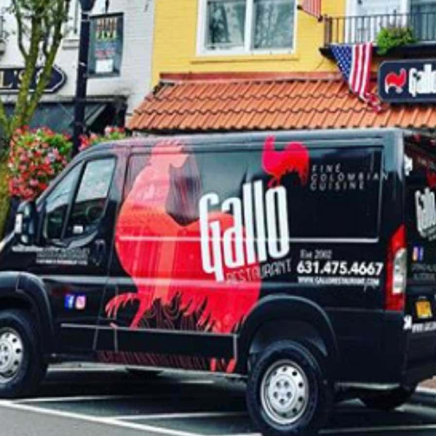 Black van with "Gallo Restaurant" signage, red rooster graphic, and contact details, parked on a street in front of a building with an American flag.