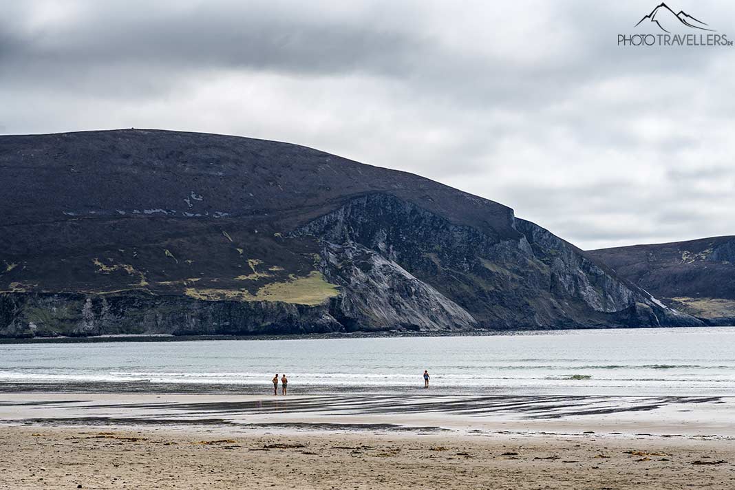 Drei Personen am weiten Keel Beach, Irland