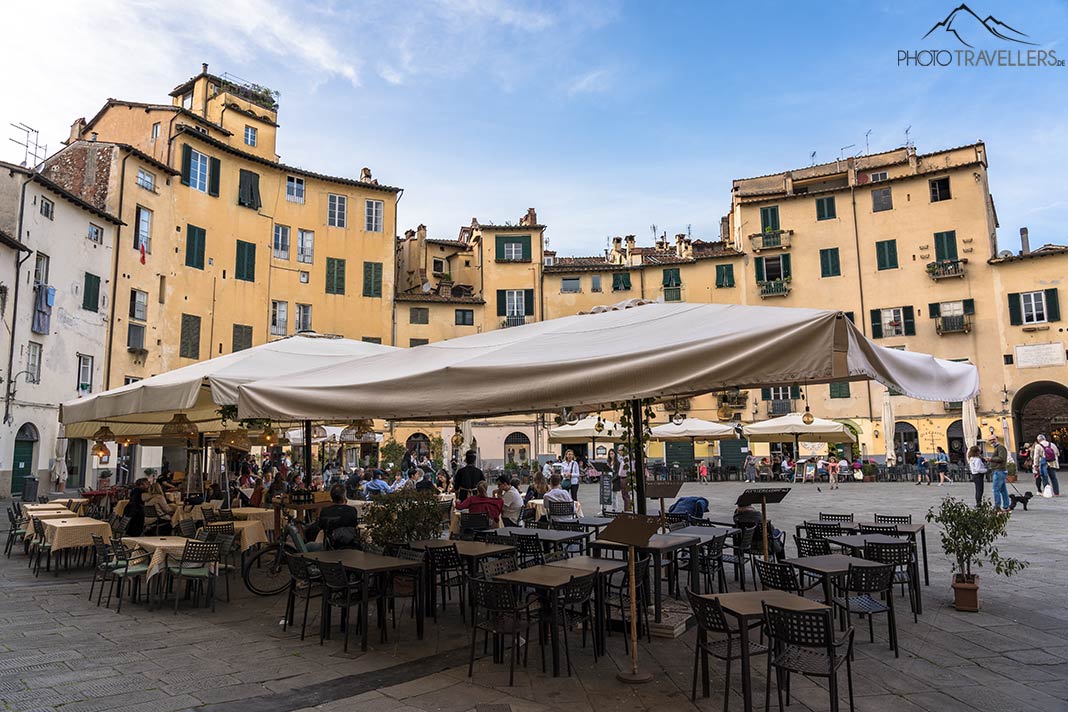 Stühle und Tische eines Restaurants auf dem Piazza dell'Anfiteatro in Lucca