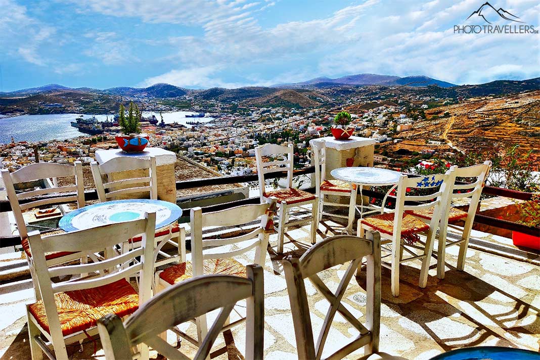 Die Tische und Stühle auf der Veranda einer Taverne in Ano Syros bieten einen Rundumblick auf die Hauptstadt Ermoupolis