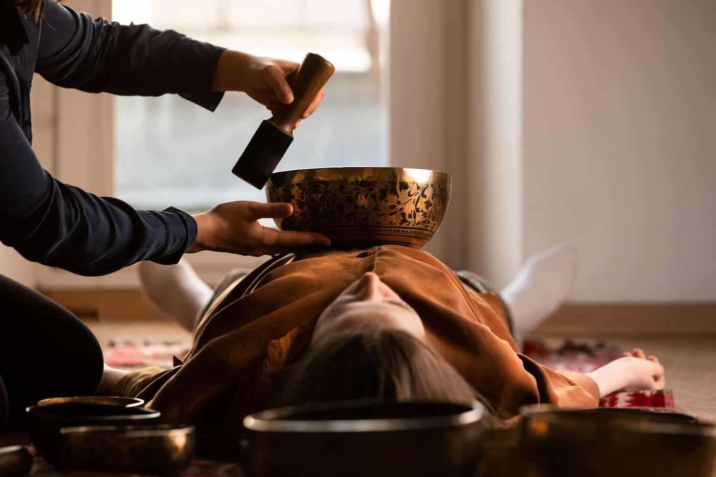 Woman receiving sound healing session with Himalayan bowl