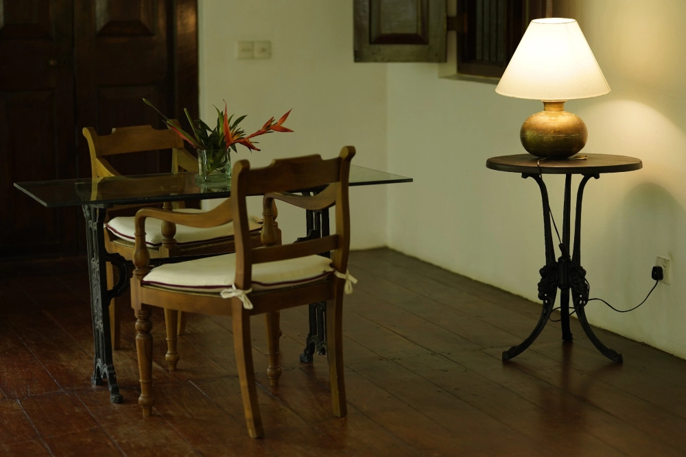 A wooden table with a lamp in the Connelian room of Adigar's manor.