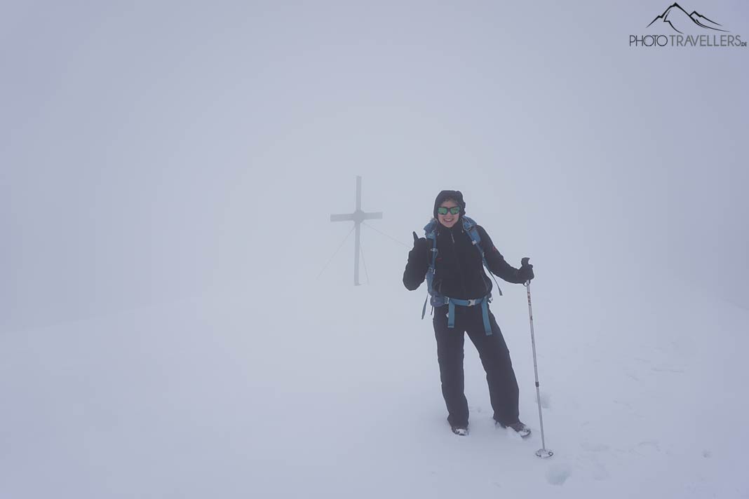 Reisebloggerin Biggi Bauer im Schnee und im Nebel vor dem Solstein-Gipfelkreuz