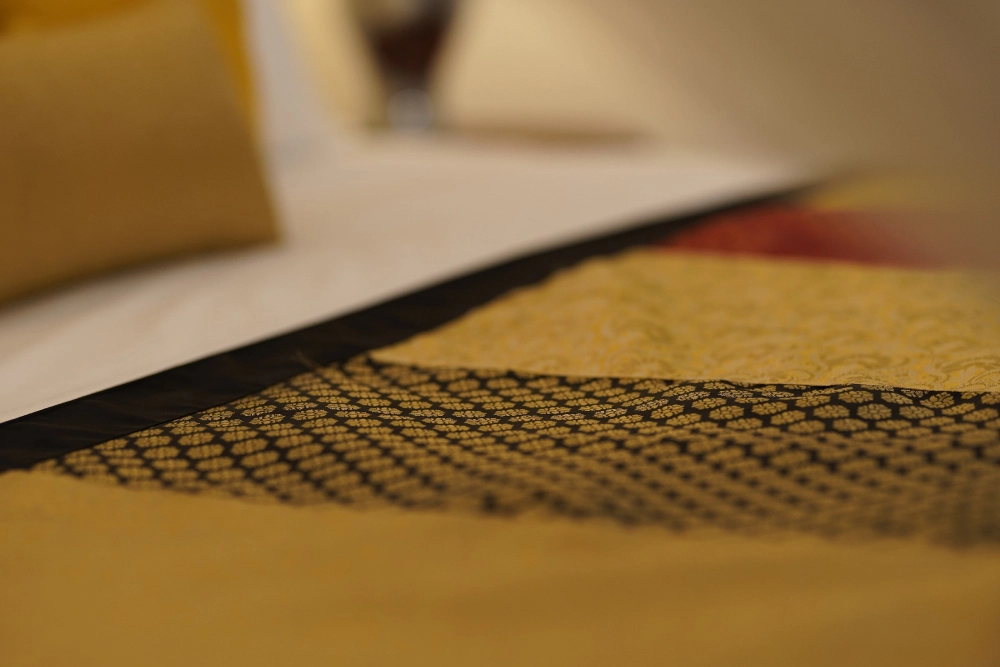 A cozy bed with a pillow and blanket in the Lime Butterfly room of Adigar's Manor.