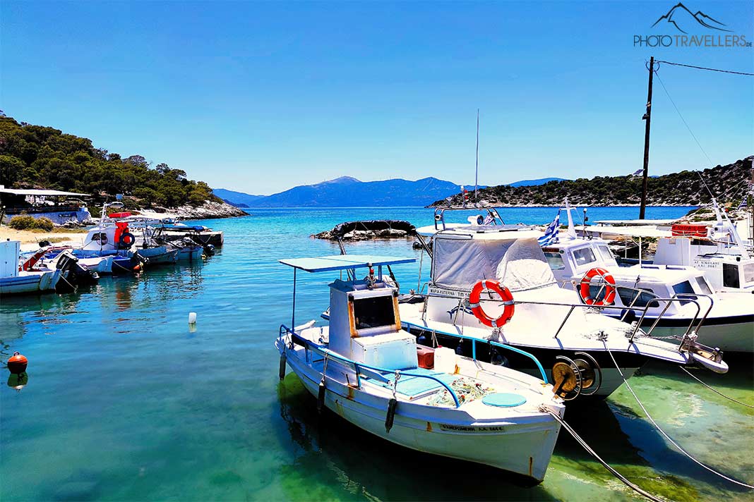Kleine Boote ankern im türkisen Wasser in der Bucht von Aponisos