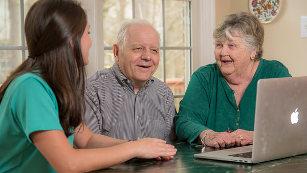 Seniors with a consultant, looking at a laptop