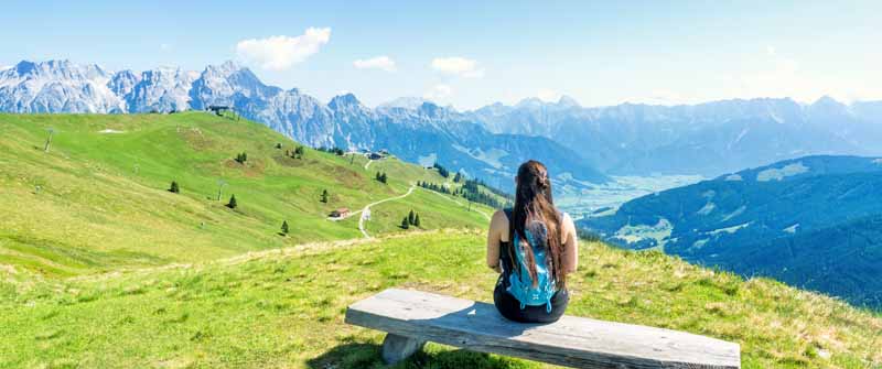 Reisebloggerin Biggi Bauer auf einer Bank auf dem Großen Asitz, eine der schönsten Wanderungen in Leogang