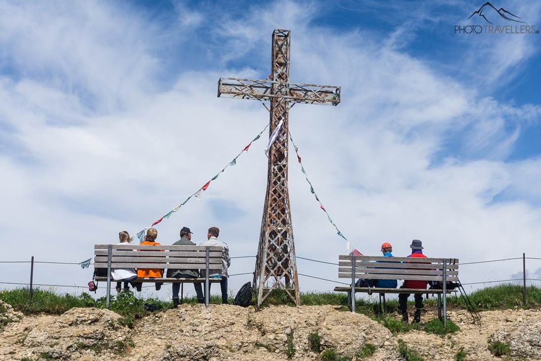 Sechs Wanderer sitzen auf zwei Bänken am Hochgrat-Gipfelkreuz