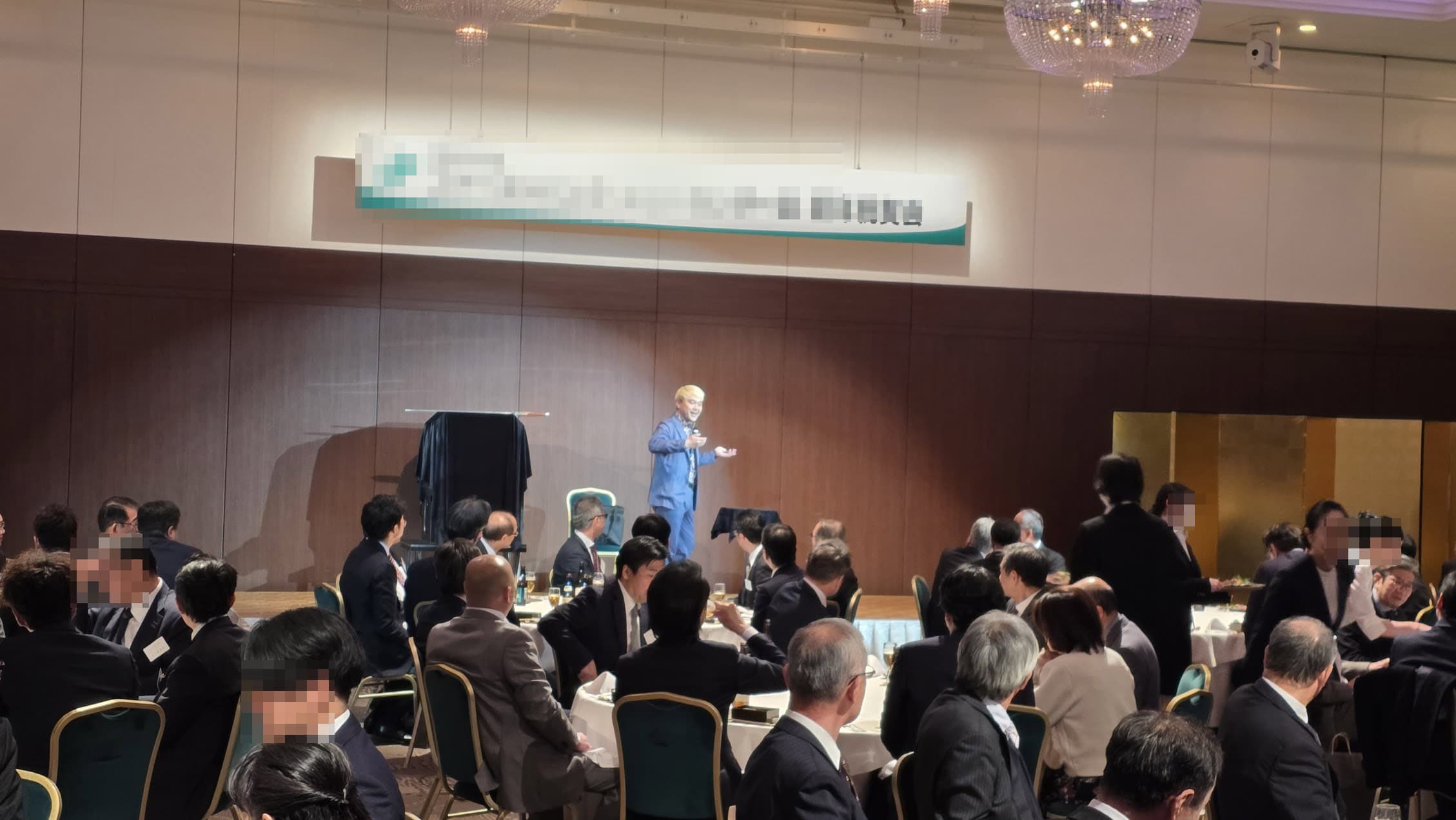 【2026年版】出張マジシャンの料金はいくら?シーン別・規模別の費用相場をプロが本音で解説 5 オークスカナルパークホテル富山のパーティー会場でステージマジックを披露するマジシャン・コンプレッサーと注目するお客様たち