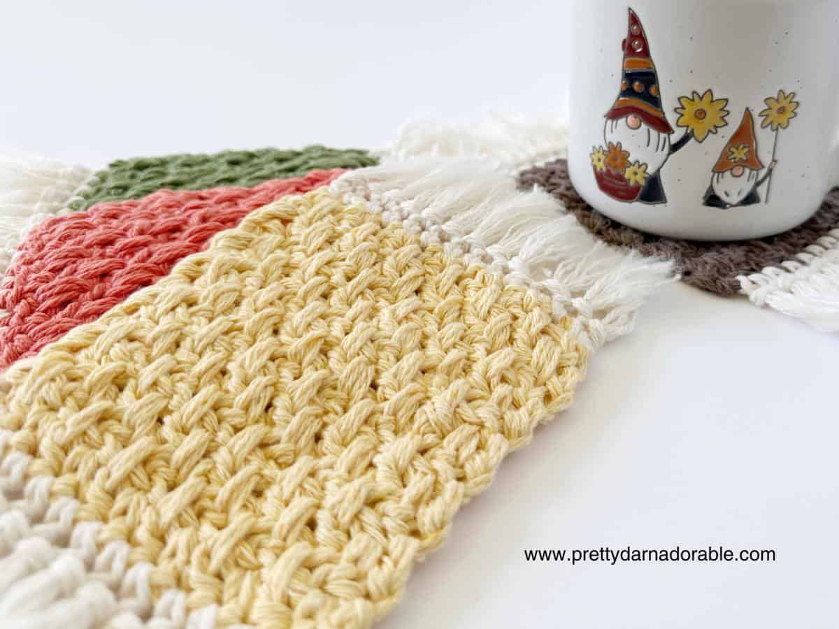 multiple coloured crochet mug rugs with fringe