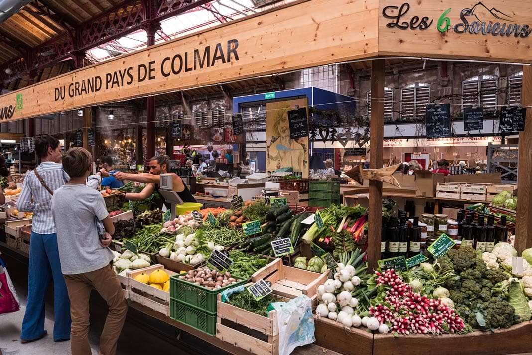 Kunden vor einem Gemüstestand in der Markthalle in Colmar