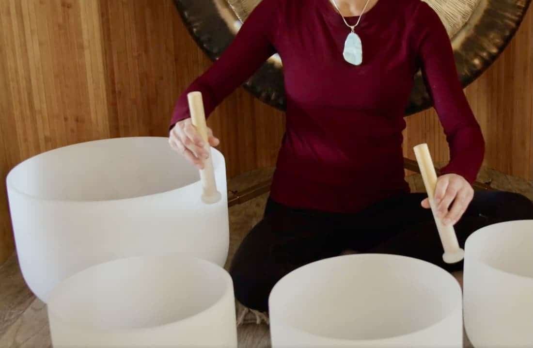 Jamie Bechtold playing two crystal singing bowls in a sound bath