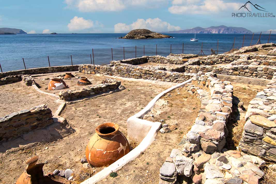 Flache Steinmauern und eine Ton-Amphore vor dem mykenischen Friedhof mit Meer im Hintergrund
