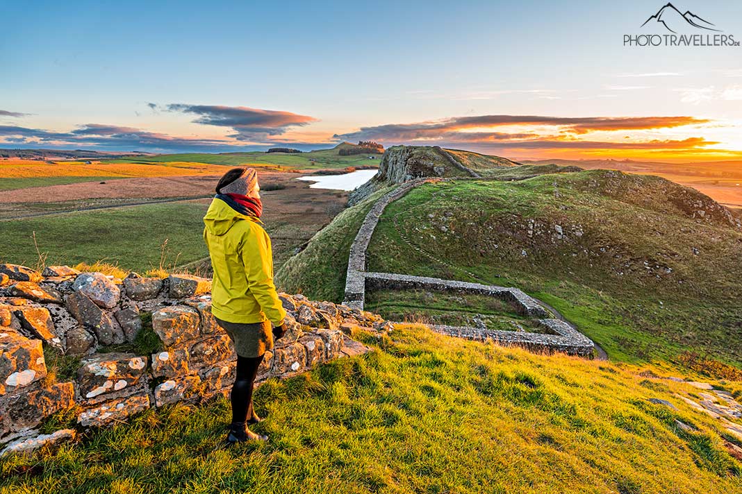 Reisebloggerin Biggi Bauer steht im Morgenlicht am Hadrianswall in England und blickt über die Landschaft