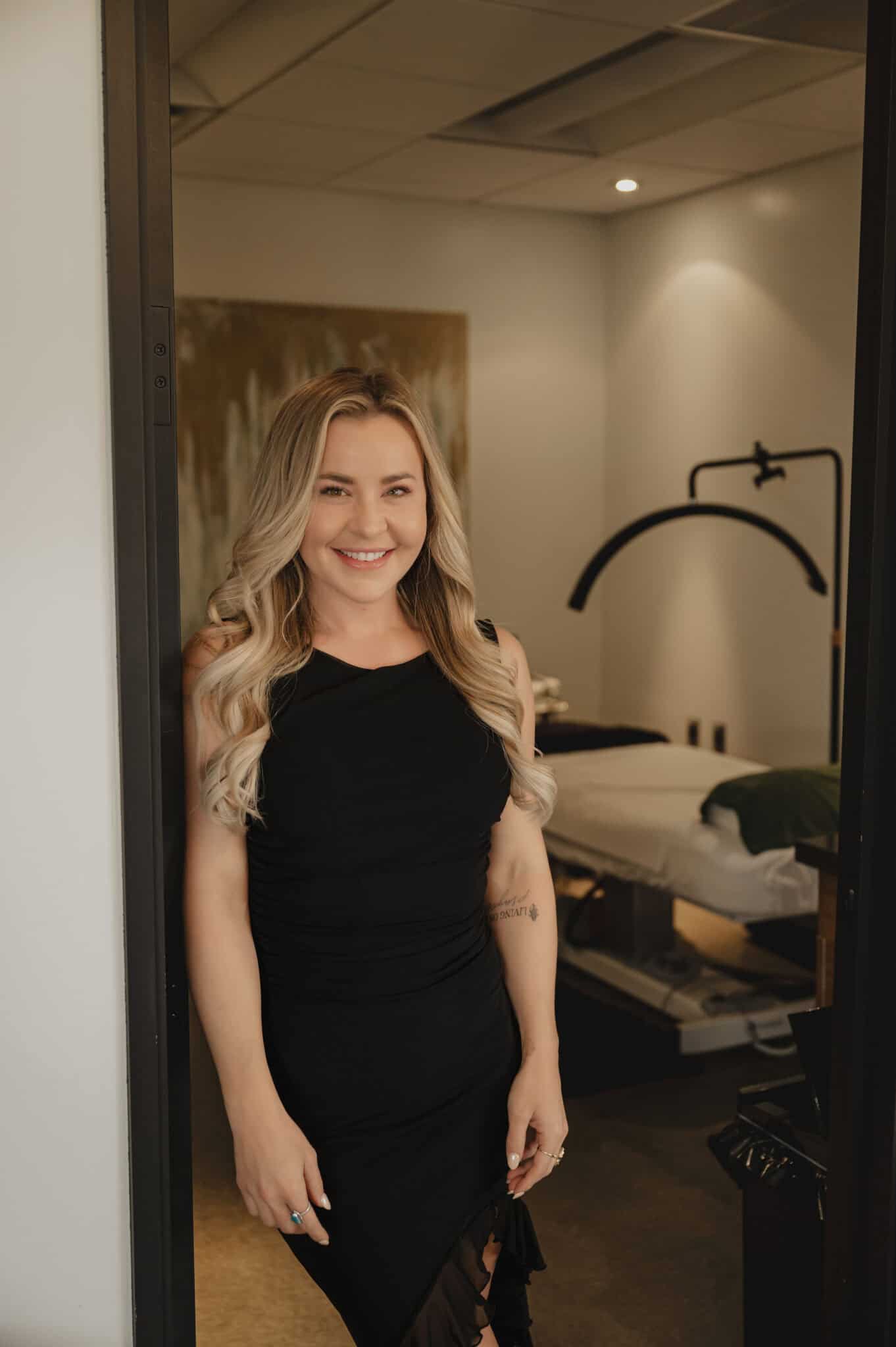 Woman smiling in a spa room doorway.