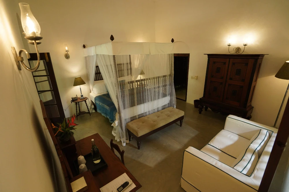 The Peacock Royal room of Adigar's manor showcasing a stylish canopy bed and a comfortable couch.