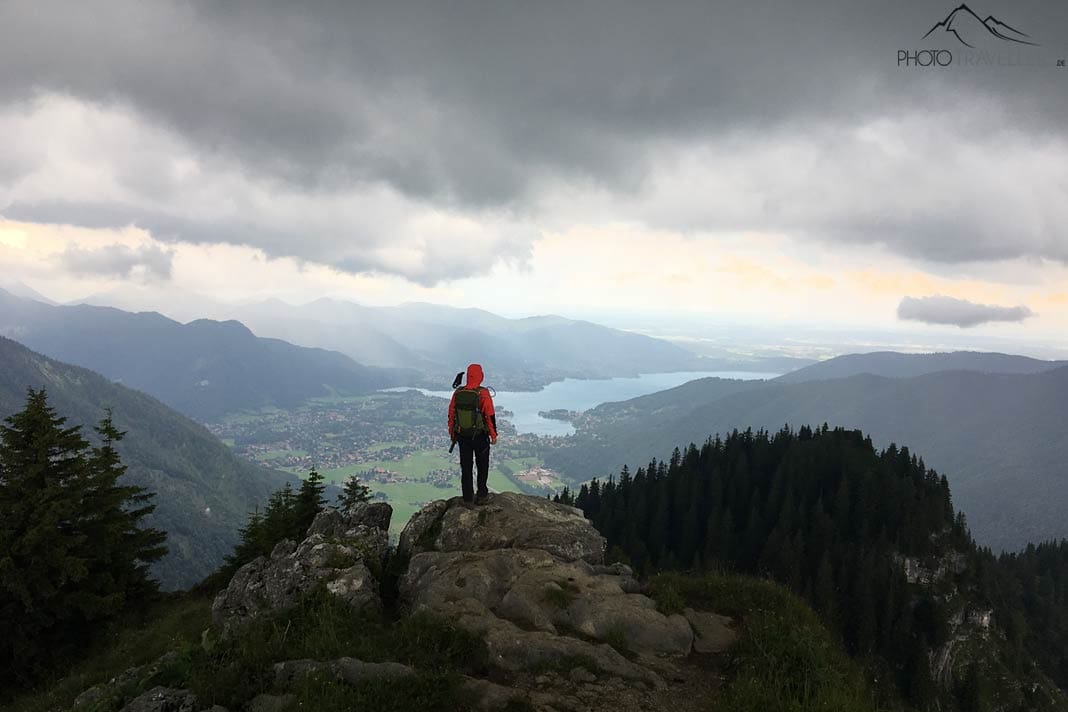 Ein Teilnehmer der Wanderleiter-Ausbildung auf einem Fels mit Blick auf den Tegernsee