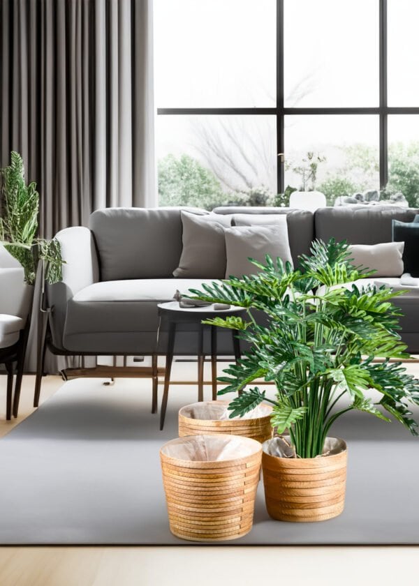 Testo alternativo: Pianta Artificiale Philodendron Selloum in un ambiente di design - La Pianta Artificiale Philodendron Selloum posizionata in un angolo di un moderno soggiorno di design, con un divano e una lampada a sospensione sullo sfondo.