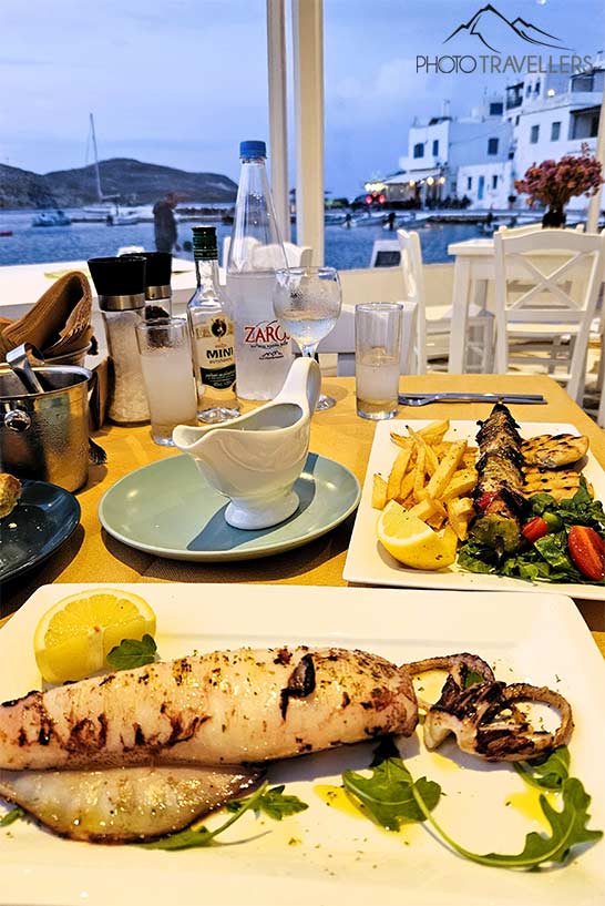 Ein gegrillter Kalmar und weitere Speisen sind an einem Lokal am Meer angerichtet