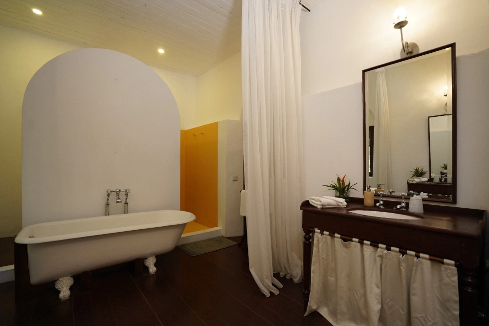 The Lime Butterfly room's bathroom at Adigar's Manor, showcasing a tub and a sink.