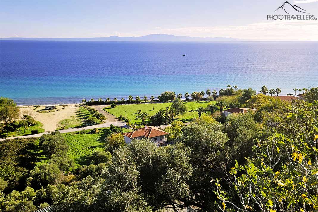 Die Küste von Afytos von oben betrachtet mit vielen Bäumen und satten Grünflächen am Meer