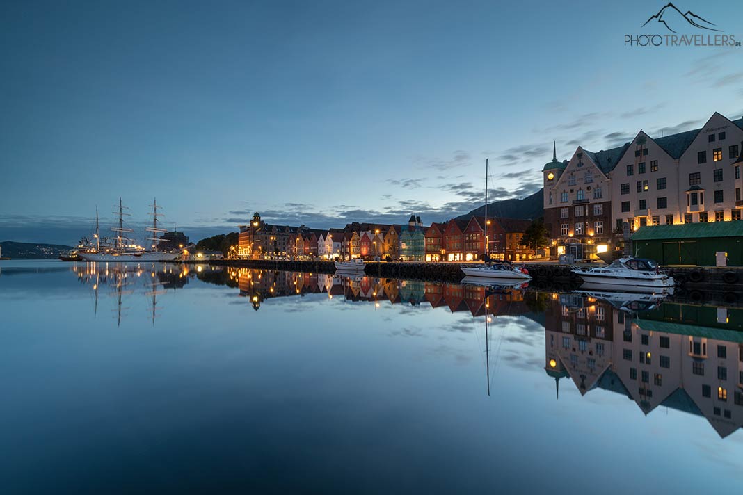 Die Häuser im Hafen der Stadt Bergen in Norwegen spiegeln sich am Morgen im glatten Wasser