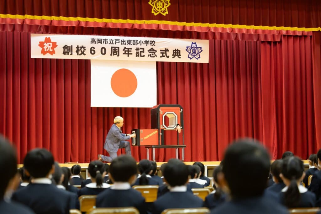 【PTA講演会 人気講師の選び方】「面白かった!」と言われる小学校・PTA講演会の3つの条件【2026年版】 3 高岡市立戸出東部小学校創立60周年記念式典の体育館ステージで大掛かりなイリュージョンを披露するマジシャン・コンプレッサー