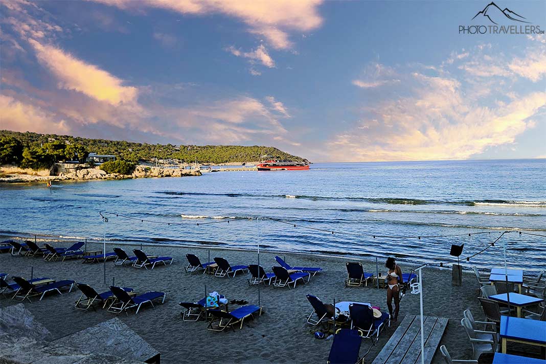 Eine Frau steht in der Abenddämmerung an den Sonnenliegen am Strand Agia Marina