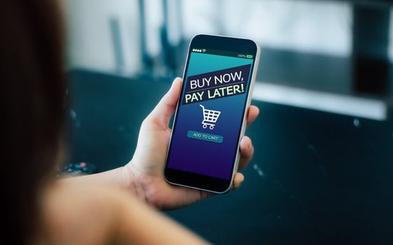 Person holding phone with BNPL grocery payment screen visible