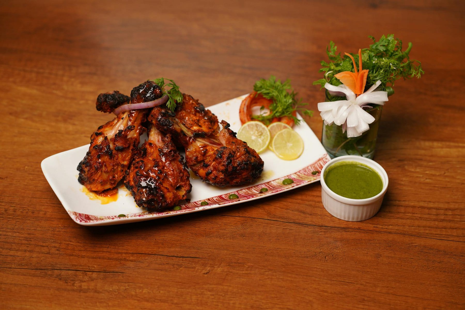 Juicy grilled chicken wings with green dipping sauce and fresh herbs, appetizingly presented.