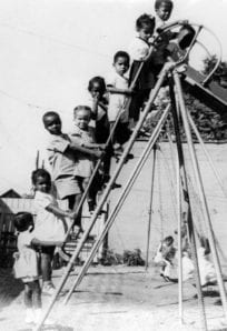 Hering House playground ph 7528 Children playing on a vintage playground slide, capturing historical moments of childhood recreation.