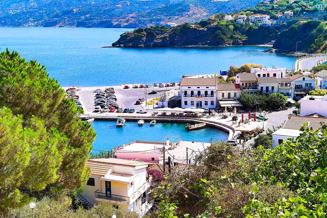 Blick von oben auf den Hafen von Evdilos mit Häusern und PKWs am Anleger