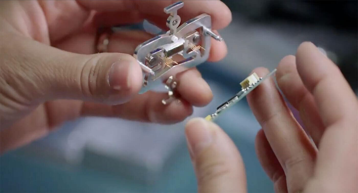 Eine Person hält die Einzelteile eines Schwingsaiten-Sensors in den Händen