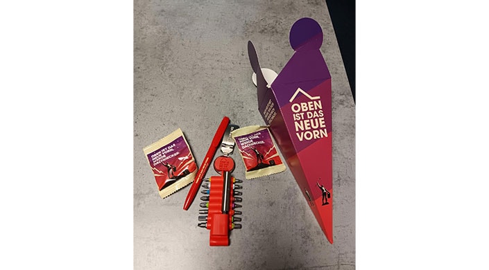 Bild von Azubi Schultüte Mehrere Werkzeuge, ein roter Stift, ein Schraubenzieher-Set und eine geöffnete lila Schachtel auf einem grauen Tisch liegend.