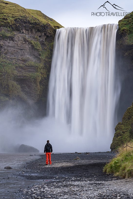 Reiseblogger Florian Westermann steht vor dem Skógafoss als Größenvergleich