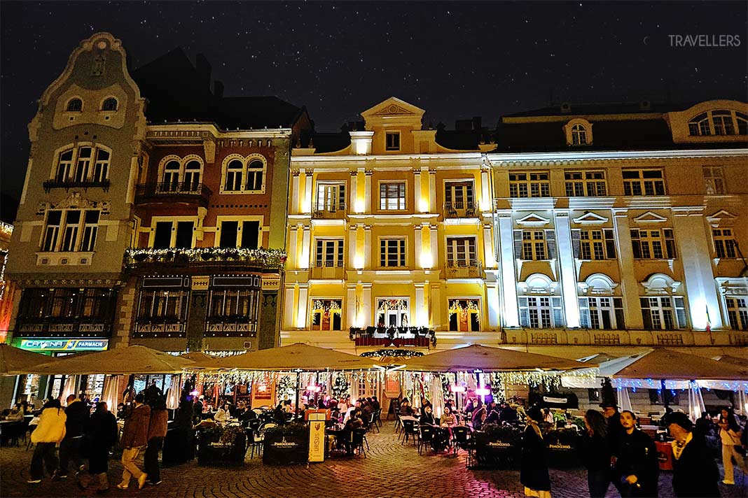 Viele Menschen flanieren in der Nacht vor den beleuchteten Herrenhäuser am Piata Unirii