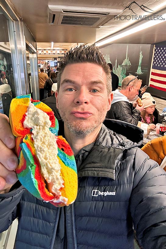 Reiseblogger Florian Westermann mit einem bunten Rainbow Bagel bei Liberty Bagels in New York