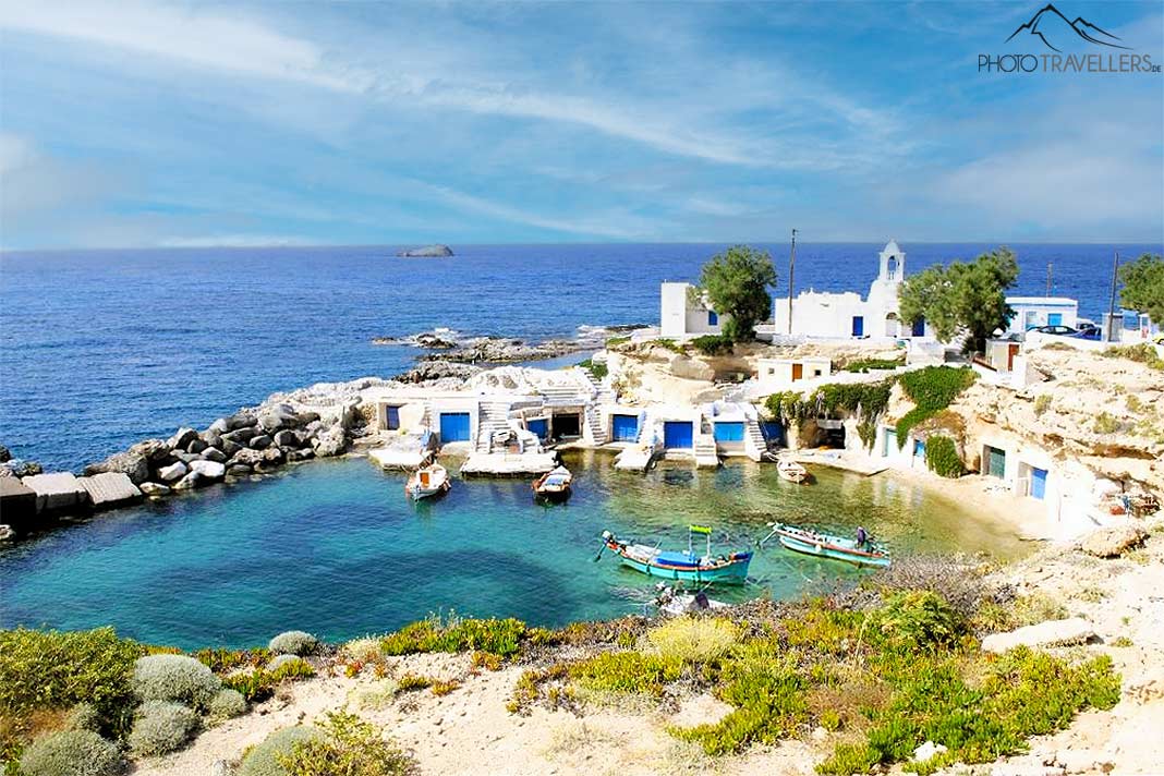 Die kleinen Bootshäuser auf Milos bilden mit ihren blauen Toren einen schönen Kontrast zur türkisfarbenen Bucht und den weißen Häusern