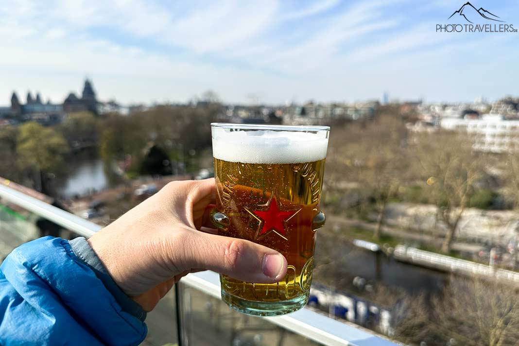 Reiseblogger Florian Westermann hält ein kleines Heineken-Bier auf der Dachterrasse der Heineken Experience in Amsterdam