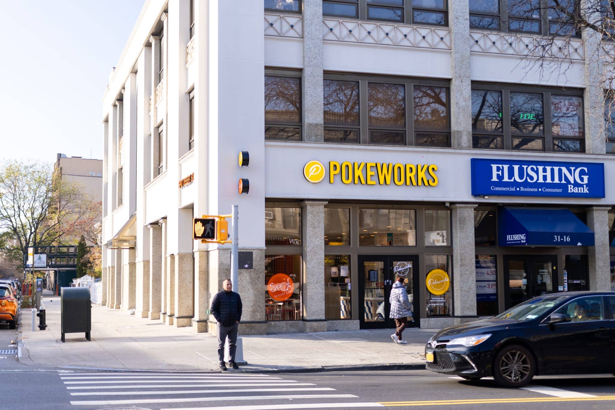 Pokeworks storefront on a Queens corner with street traffic and illuminated signage. Expressing importance of franchise real estate site selection