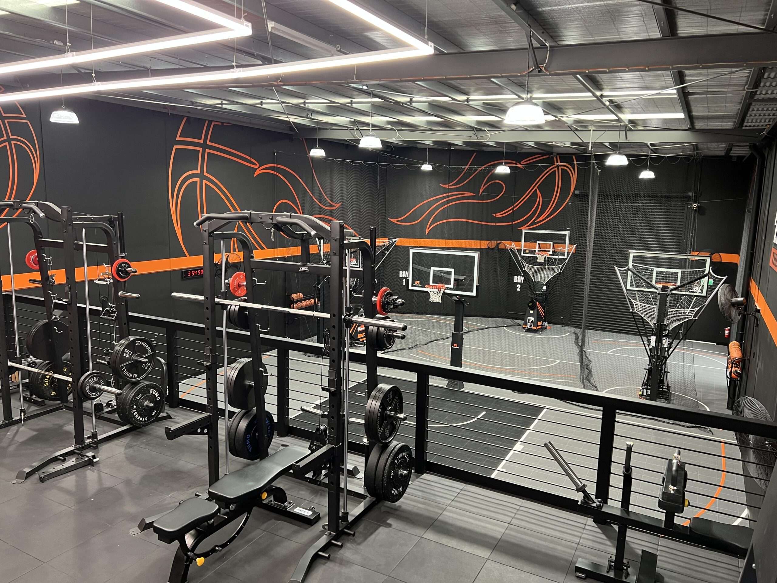 Modern indoor basketball training facility with gym equipment and multiple basketball hoops.