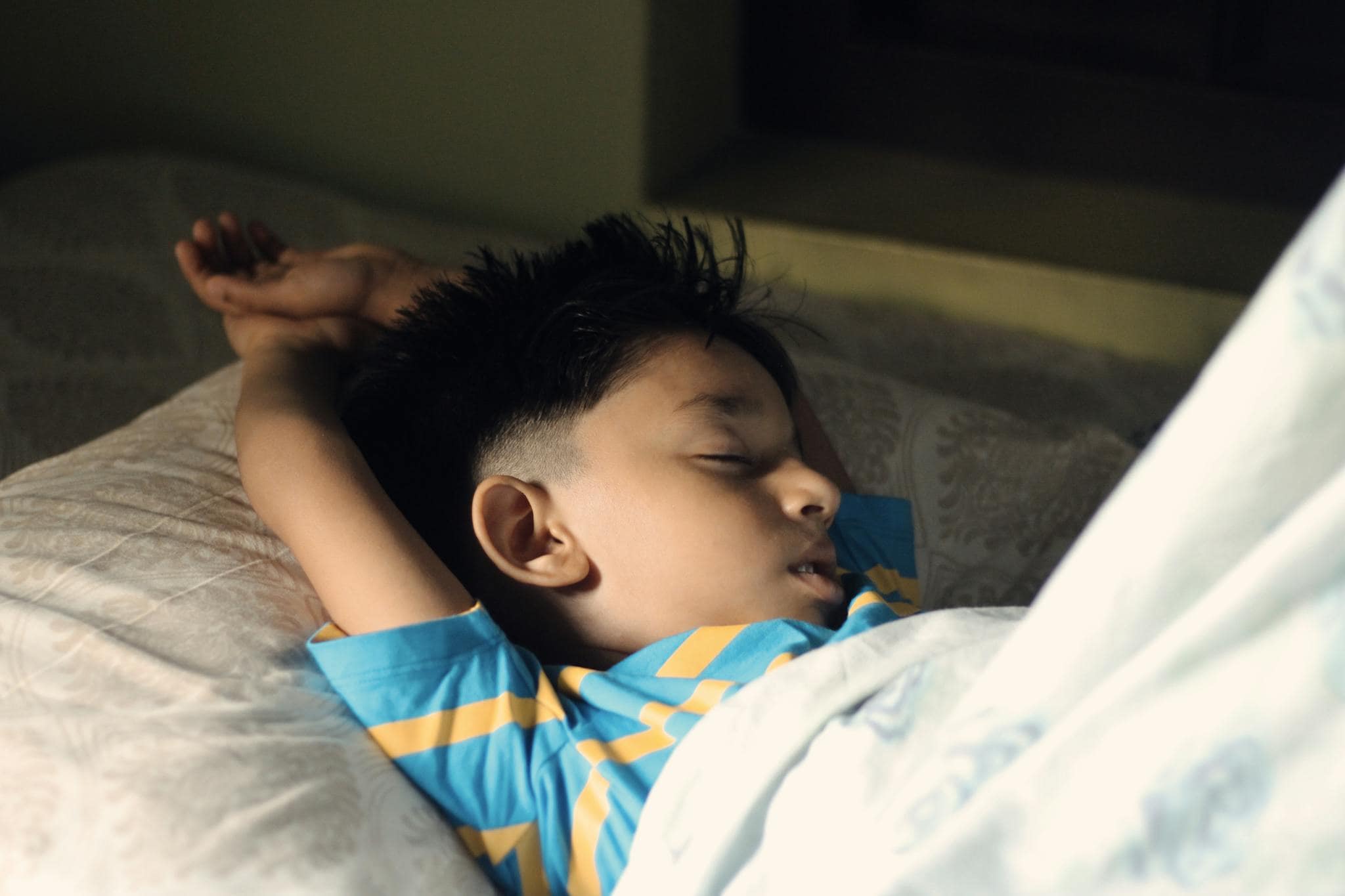A young boy peacefully sleeping in a cozy bedroom setting, captured indoors.