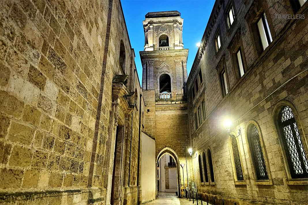 Beleuchtete Steinfassade mit einem mehrstöckigen Turm in der Altstadt von Brindisi